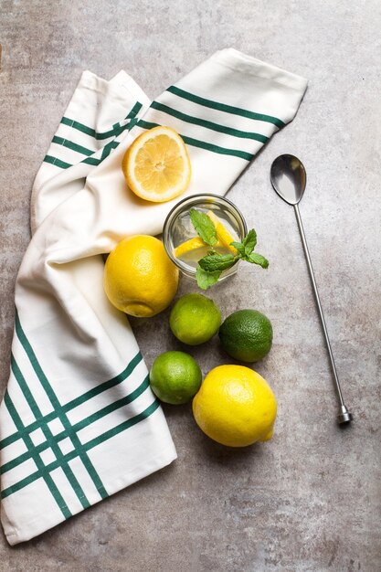 Limes lemons and a glass of lemonade on a marble counter