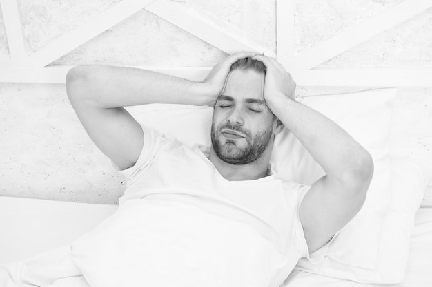 Limitare i sonnellini mattutini sveglia uomo che dorme camera da letto bianca accogliente fine settimana a casa tempo per rilassarsi ragazzo aveva notte insonne concetto di salute maschile concetto di tranquillità uomo stanco dormire a letto