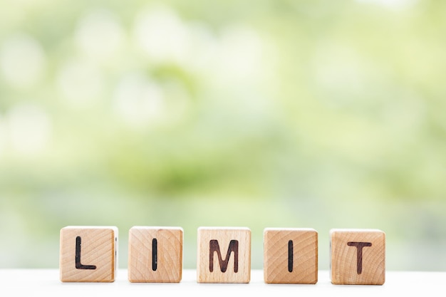 LIMIT woord is geschreven op houten kubussen op een groene zomerachtergrond Close-up van houten elementen