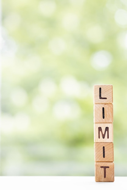 LIMIT woord is geschreven op houten kubussen op een groene zomerachtergrond Close-up van houten elementen