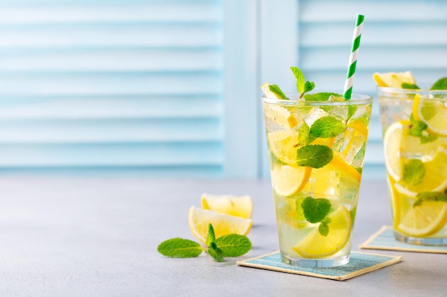 Limonade citroen ijsthee munt cocktail in glas Blauwe achtergrond Close-up kopie ruimte