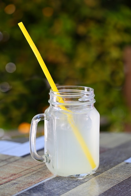 Limonade vers in een pot met een handvat en een rietje op tafel.