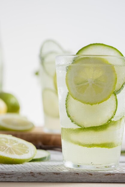 Limonadefles en een glas geserveerd met plakjes citroen en komkommer op een lichte achtergrond Kopieer ruimte