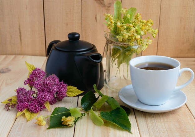 Linden flowers and tea on a light wood.