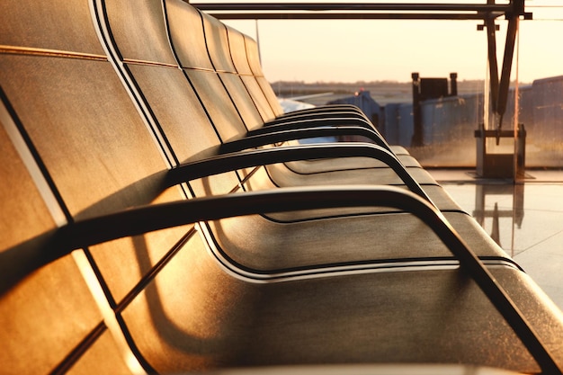 Line of empty chairs in international airport at sunset