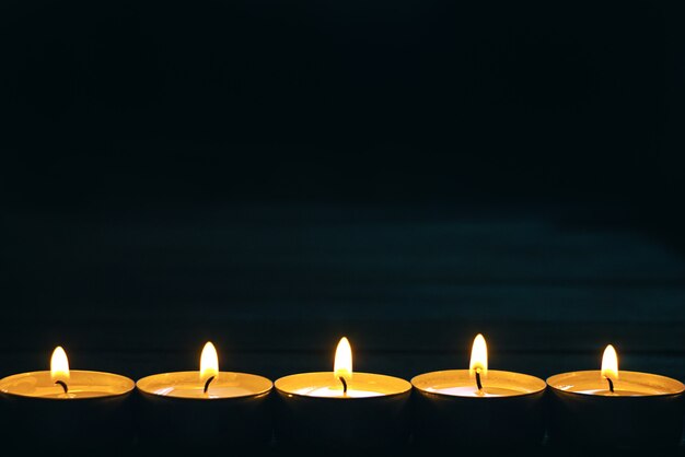 Line of five burning candles on dark