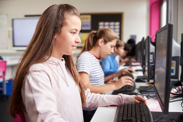 Foto linea di studenti delle scuole superiori che lavorano su schermi in classe di computer