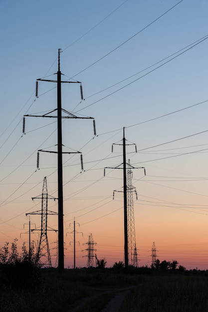 A line of poles with high voltage wires at sunset