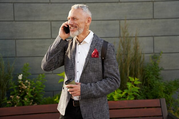 On the line portrait of happy successful middle aged businessman in stylish suit smiling while