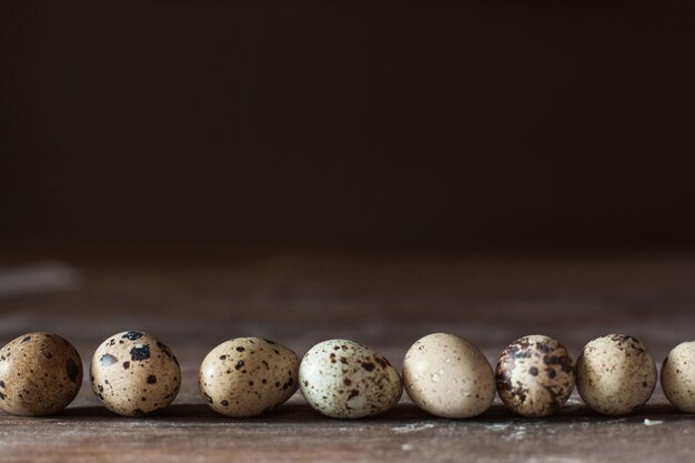 Line of quail eggs on wooden table free space.