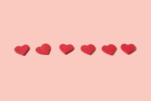 Premium Photo | Lined up and centered red hearts made from modeling clay on  a pastel pink background with copy space