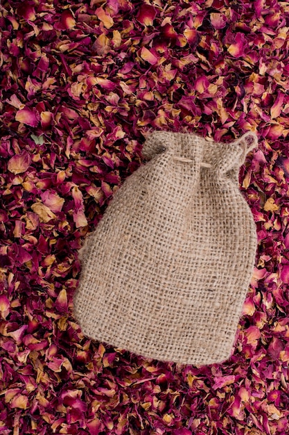 Linen sack on background of dried rose petals