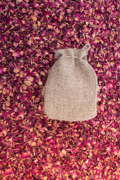Linen sack placed on background of dried rose petals