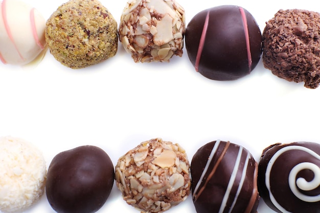 Lines of assorted chocolate candies on a white background