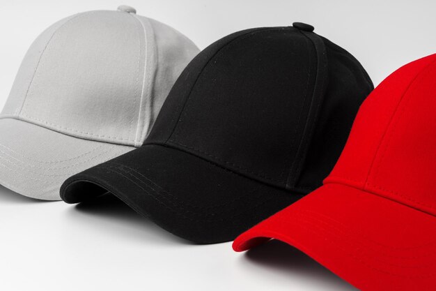 Lineup of four blank baseball caps in red white and black on a white background