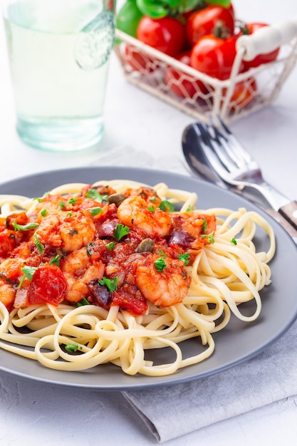 Linguine Puttanesca pasta with shrimps in spicy tomato basil sauce