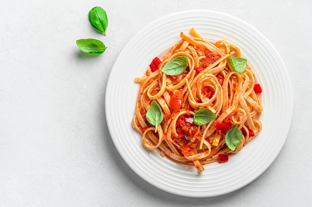 Linguini pasta met tomatensaus en basilicum op een grijze achtergrond met een kopie ruimte