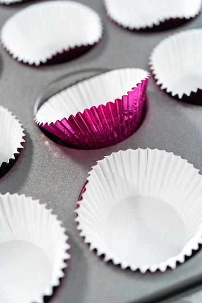 Lining cupcake pan with cupcake liners to bake red velvet cupcakes.