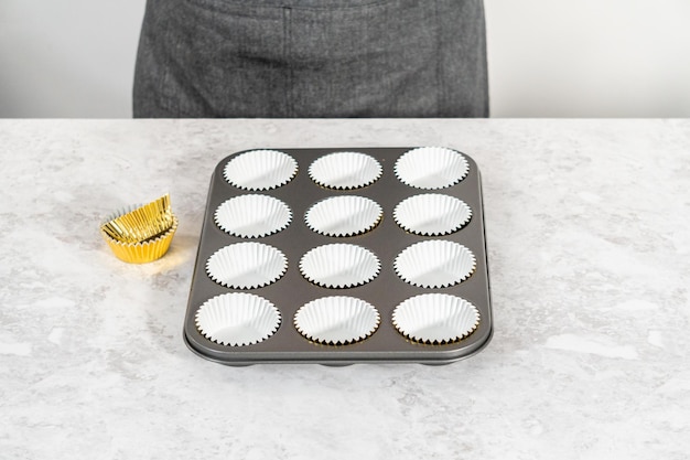 Foto foderare la tortiera con pirottini di alluminio per cuocere i cupcakes s'mores.