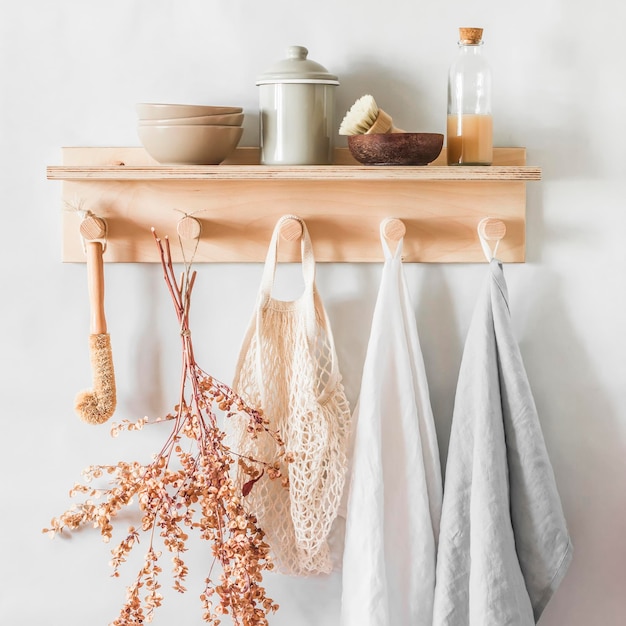 Linnen handdoeken op een houten plank met kommen keramische potborstels gedroogde bloemen in een gezellige keuken in scandinavische stijl