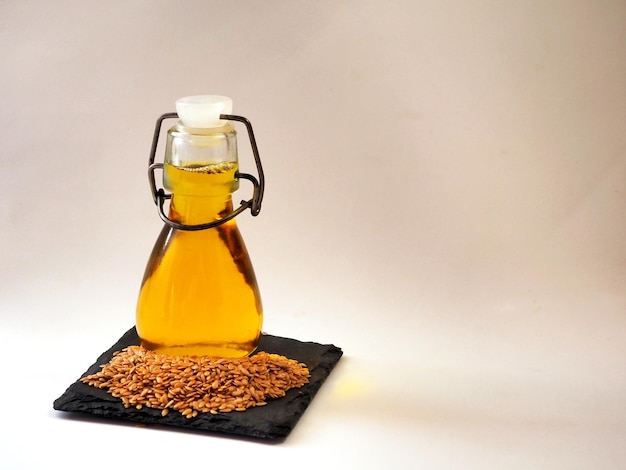 Linseed oil in a transparent bottle and golden flax seeds