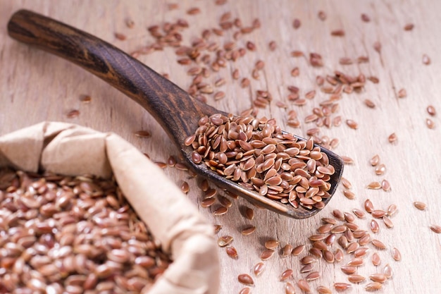 Linseed seeds in container and spoon on the table