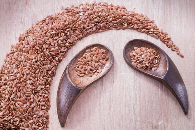 Linseed seeds in container and spoon on the table