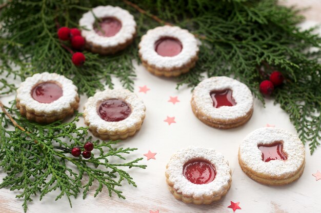 Linzer cookies in a Christmas decoration on a wooden surface.