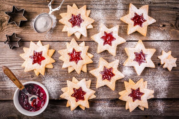 Linzer kerstkoekjes met frambozenjam op een rustieke houten ondergrond