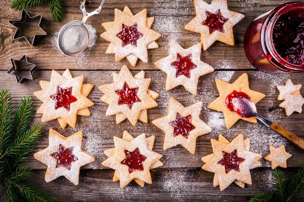 Linzer kerstkoekjes met frambozenjam op een rustieke houten ondergrond