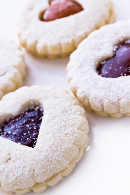 Linzer Torte cookies on white background with powdered sugar sprinkled on top.