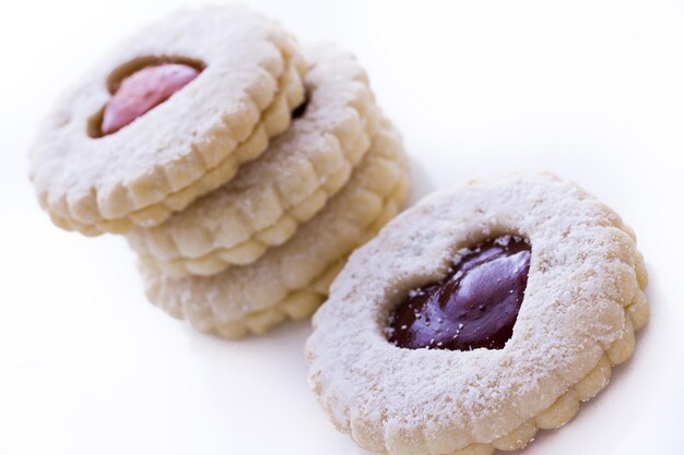 Linzer Torte cookies on white background with powdered sugar sprinkled on top.