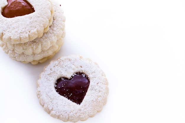 Linzer Torte cookies on white background with powdered sugar sprinkled on top.