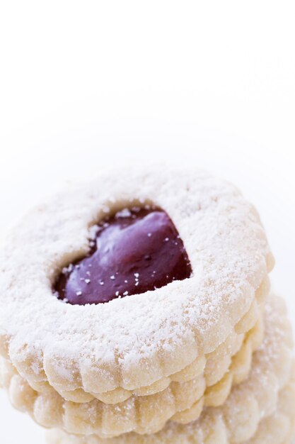 Печенье Linzer Torte на белом фоне с сахарной пудрой, посыпанной сверху.