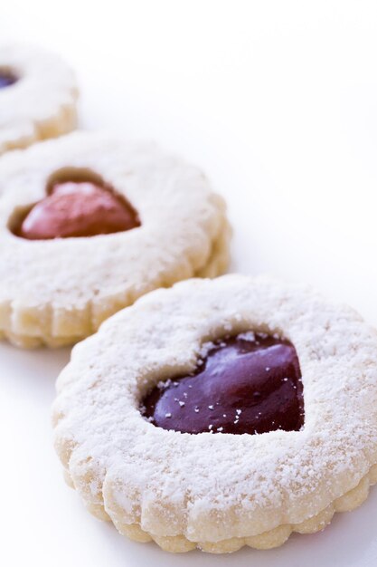 Linzer Torte-koekjes op witte achtergrond met poedersuiker erop gestrooid.