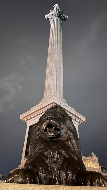 A lion statue stands in front of a monument in london