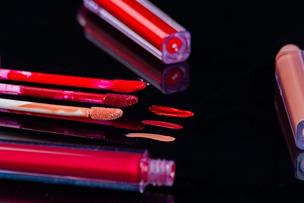 Lip gloss strokes on black reflective surface colored glass sticks for brushes