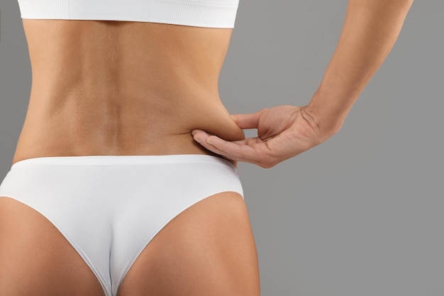 Liposuction Concept Rear View Of Woman Pinching Skin On Her Waist Side