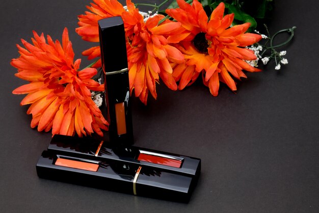 Foto lippenstift en oranje bloemen voor vrouwen