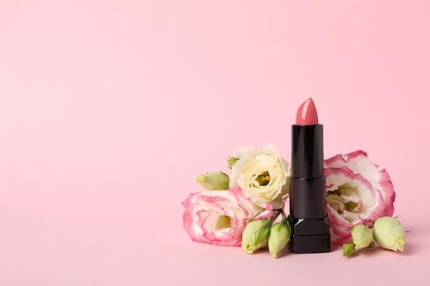 Lipstick and flowers on pink background