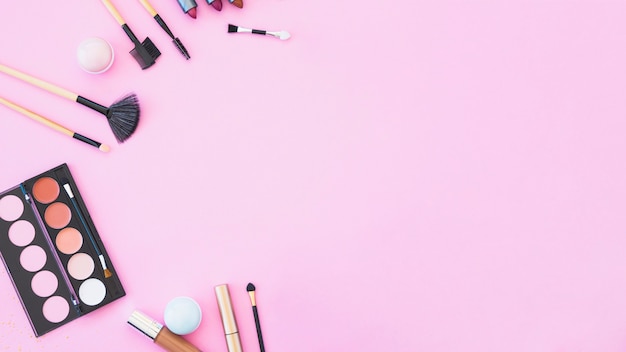 Lipstick; makeup brushes and palette on pink background