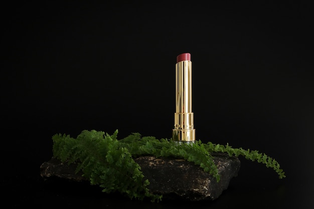 Lipstick standing on stone podium. Lipstick presentation on the black background.