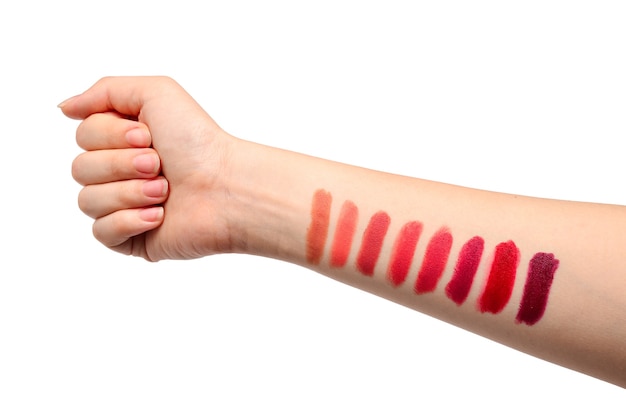 Lipstick swatches on woman hand isolated on white background.