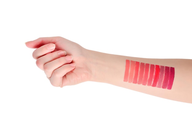 Lipstick swatches on woman hand isolated on white background.