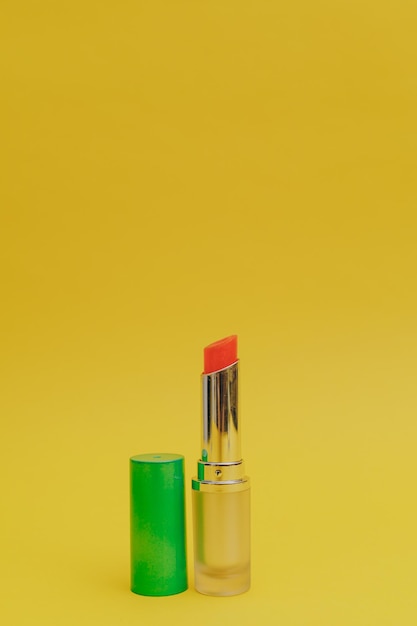 Lipstick with a bright green cap on a yellow background