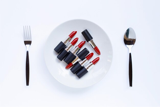 Lipsticks on white dish with fork and spoon on white 