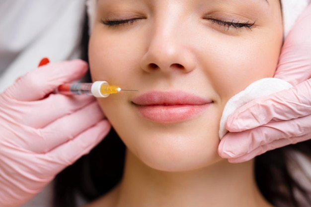 Lipvormcorrectieprocedure in een schoonheidssalon De specialist maakt een injectie op de lippen van de patiënt Lipvergroting