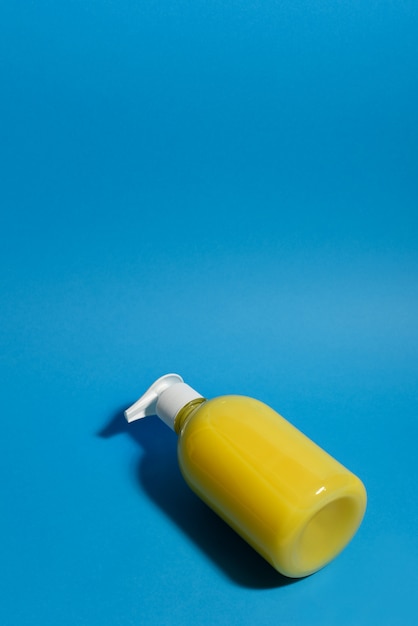 Photo liquid antibacterial dispenser soap on a blue background. yellow banana soap for washing hands. stop the virus. antiviral hygiene. copy space.