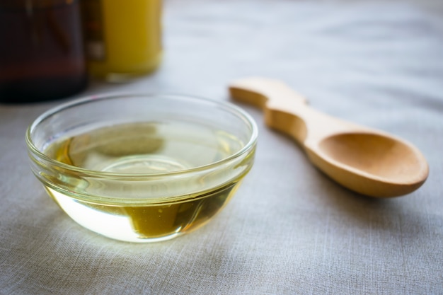 Liquid coconut MCT oil in round glass bowl with wooden spoon