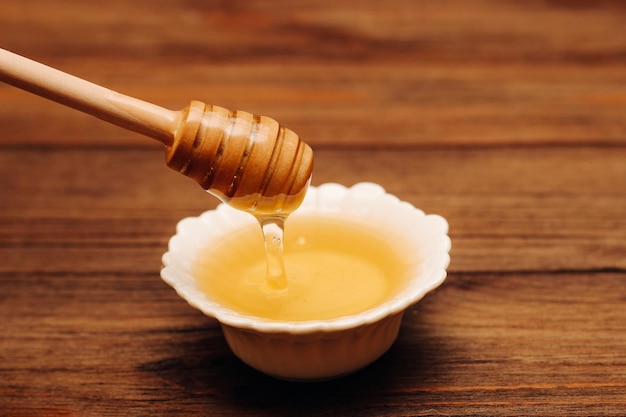 Liquid fresh linden honey in a plate with a wooden honey spoon